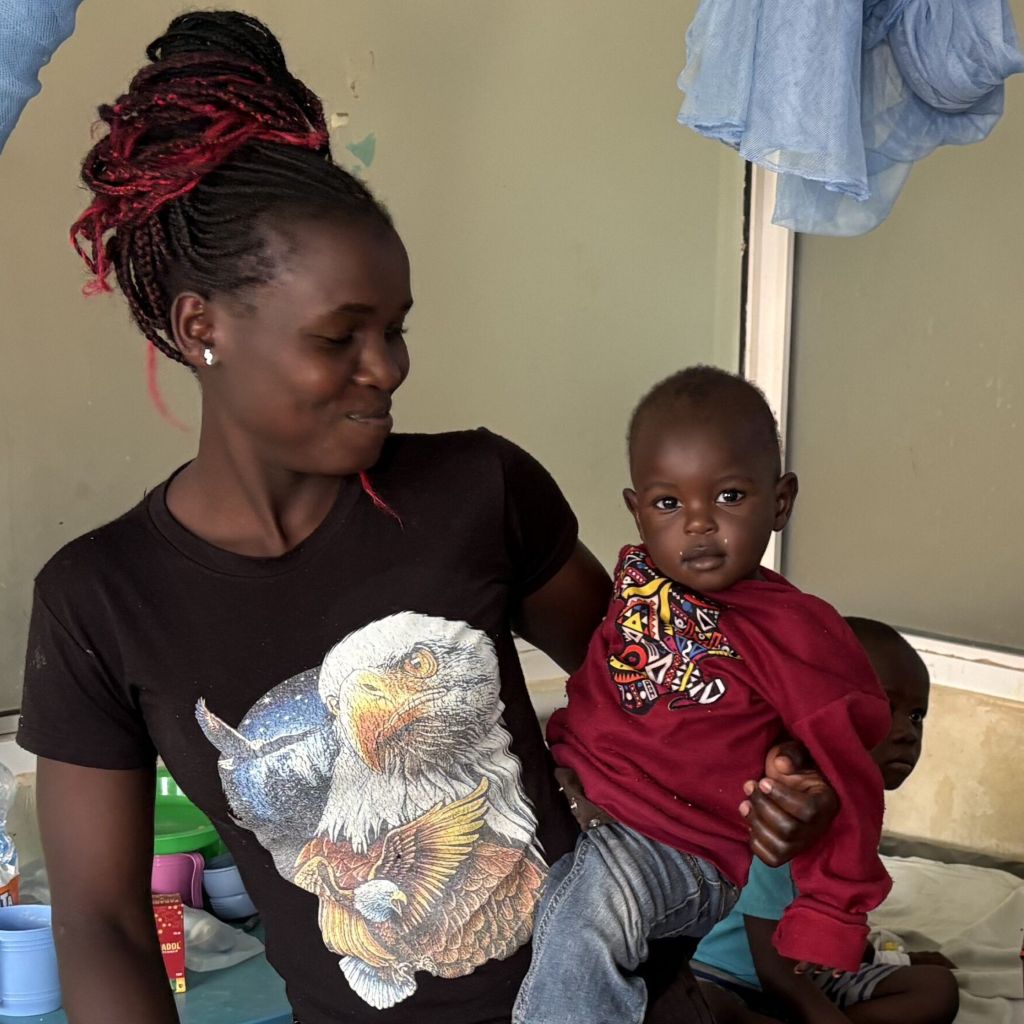 Mother holding young child in a clinical setting in Kenya